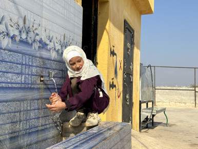 Syrian girl is washing hands at non formal education center in Syrian camp.