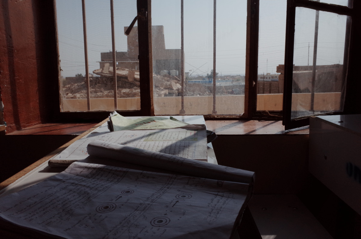 A classroom window peers over a destroyed building in Sinjar