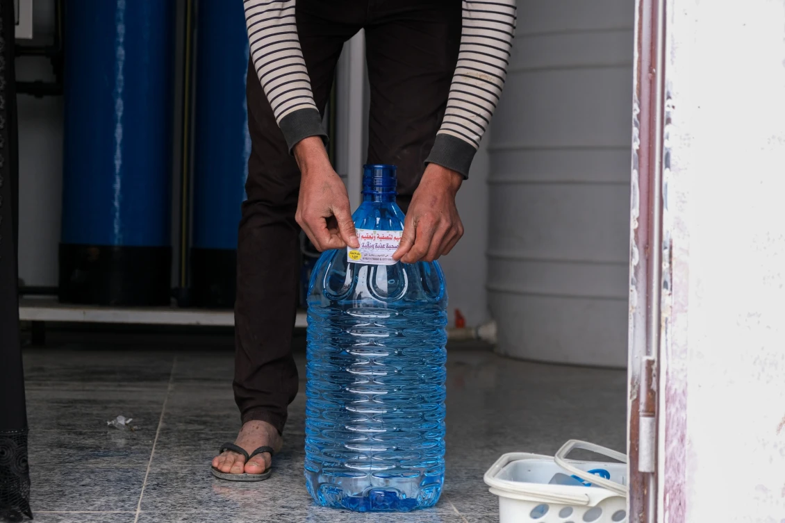 Athir pasting a their brand on the water gallons before selling them to people in his hometown Beiji, Iraq.