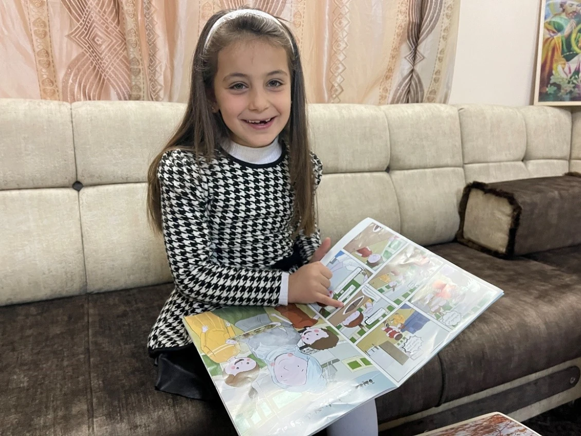 Stella pointing to her favorite characters in the comic book given to her by PIN